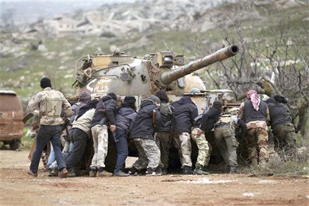 مسلحون من «صقور الشام» يحتمون بدبابة خلال اشتباك مع القوات السورية في جبل الاربعين في ريف ادلب امس (رويترز)