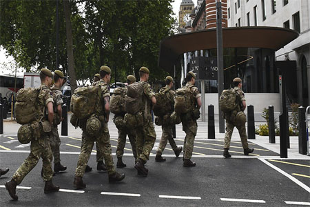 British soldiers arrive by bus and head toward a building next to New Scotland Yard police headquarters near to the Houses of Parliament in central London on May 24, 2017.