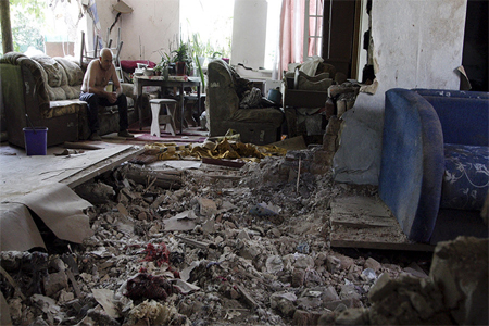 A local resident sits amidst debris at his damaged house, which according to locals was hit by recent shelling, in Donetsk, Ukraine, June 22, 2015