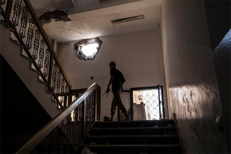 A fighter of the Libyan forces affiliated to the Tripoli government walks to his position, inside the Libyan Central Bank building in Sirte, Libya, Tuesday, Sept. 27, 2016. (AP)