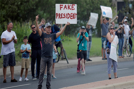 A protester stands by the motorcade transporting U.S. President Donald Trump to a briefing on Tropical Storm Harvey relief efforts at the Texas Department of Public Safety Emergency Operations Center in Austin, Texas, U.S., August 29, 2017.