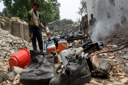 Afghan policemen inspect a destroyed police checkpoint, which a NATO aircraft had mistakenly attacked during a clash between Afghan special forces and a group of Taliban fighters at the checkpoint, at the Bati Kot district of Nangarhar province, August 1, 2013