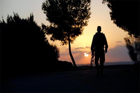 Israeli soldier walks near the border line