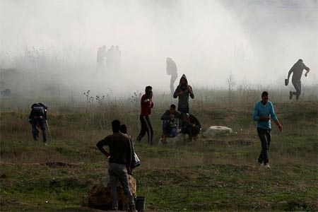 Palestinian demonstrators react to tear gas fired by Israeli troops during clashes near the border with Israel in the east of Gaza City.
