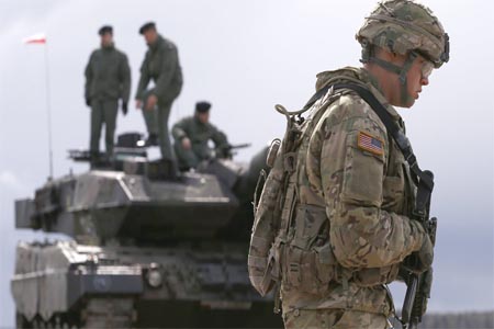 A US soldier walks to the welcoming ceremony for US-led NATO troops at polygon near Orzysz, Poland on 13 Apr. 2017