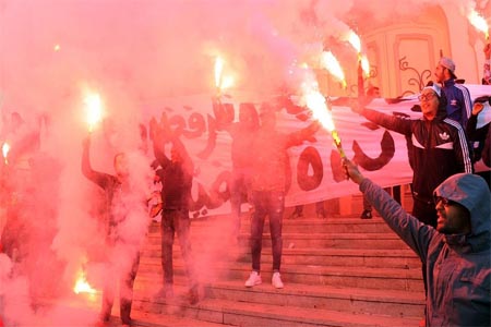 Tunisians carry flares and shout slogans against the government in Tunis.