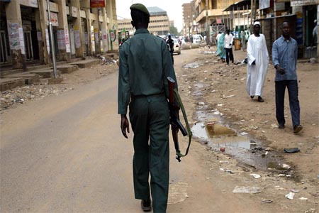 An armed policeman patrols the streets of the Sudanese capital .