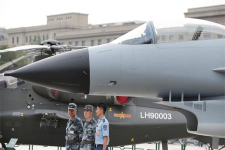 Chinese Soldiers stand next to a J-10 fighter jet.