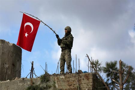 A Turkish soldier waves a flag on Mount Barsaya, northeast of Afrin.