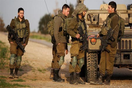 Israeli soldiers stands near a military jeep next to the border fence with the southern Gaza Strip near Kibbutz Nirim.