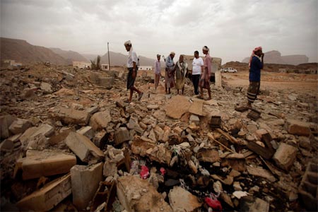 Tribesmen stand on the rubble of a building destroyed by a drone strike, that targeted suspected al-Qaeda militants in Yemen.