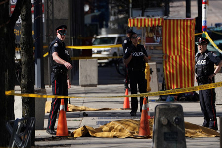 Police officers stand near covered bodies after a van struck multiple people at a major intersection in north Toronto, Ontario, Canada, April 23, 2018.