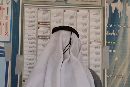 An Iraqi man checks for his name on a voter registration list before casting his ballot in parliamentary elections at a polling site.