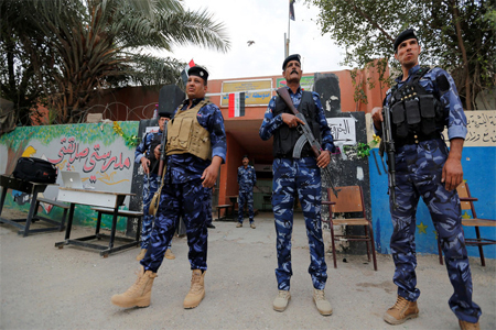 Iraqi security forces stand guard outside a polling station during the parliamentary election in the Sadr city district of Baghdad onMay 12, 2018.