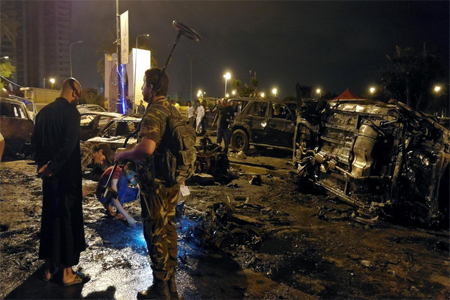 People look at the remnants of vehicles at the scene of the car bombing in Benghazi, Libya.