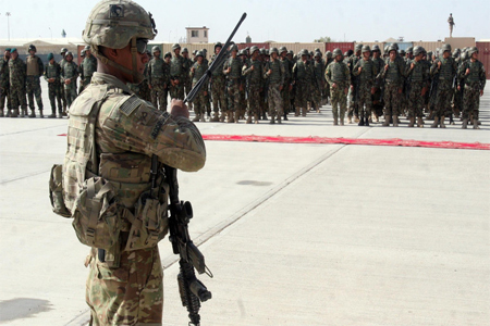 In this July 24, 2016 photo, a US military personal stands guard during a graduation ceremony in Lashkargah.