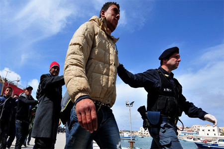 Policemen escort Tunisians would-be immigrants who are waiting to be identified on the Italian island of Lampedusa.
