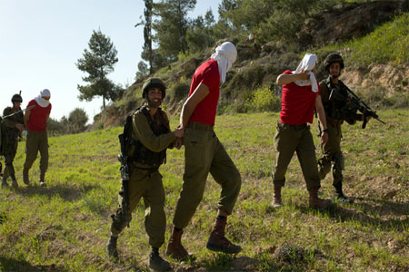 Israeli soldiers detain soldiers in red t-shirts, playing the role of Palestinian rioters, during a drill near the West Bank city of Hebron on March 1, 2015, organized by the Israeli army to simulate dispersing of riots and crowd control (AFP Photo / Menahem Kahana)
