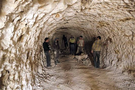 مسلحون يحفرون كهفا للاختباء داخله في قرية اللطامنة في ريف حماه أمس (رويترز)