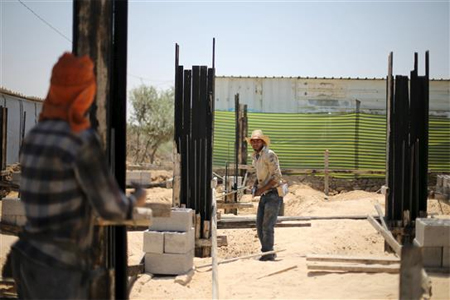 فلسطينيان يعملان في بناء منزل في غزة أمس (رويترز)
