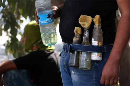 فلسطيني يضع قنابل مولوتوف على جانبه خلال الاشتباكات مع قوات الاحتلال على حاجز الحوارة قرب نابلس امس (ا ف ب)