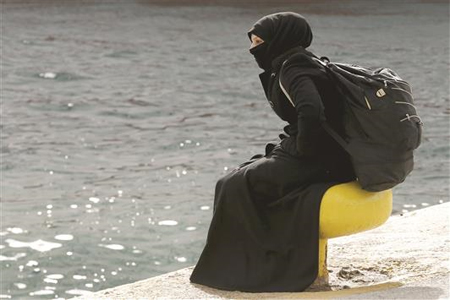 لاجئة سورية تستريح بعد انتقالها من جزيرة لسبوس اليونانية إلى مقربة من أثينا أمس (رويترز)