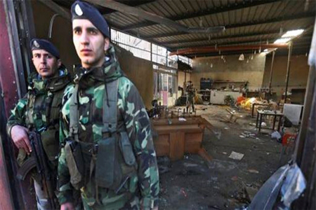 Lebanese army soldiers stand guard at the entrance to a coffee shop that was damaged in a suicide bombing Saturday night. (AP)