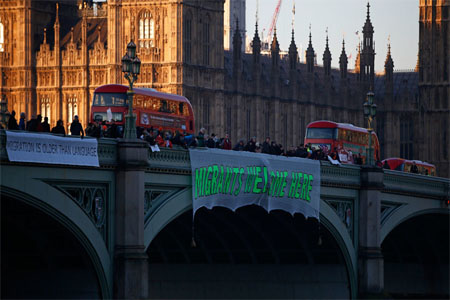 Demonstrators hang a banner that reads "Migrants Welcome Here" from Westminster Bridge during a protest against the inauguration of Donald Trump as U.S. President, in London, Britain, January 20, 2017.