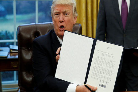 U.S. President Donald Trump holds up the executive order on withdrawal from the Trans Pacific Partnership after signing it in the Oval Office of the White House in Washington January 23, 2017